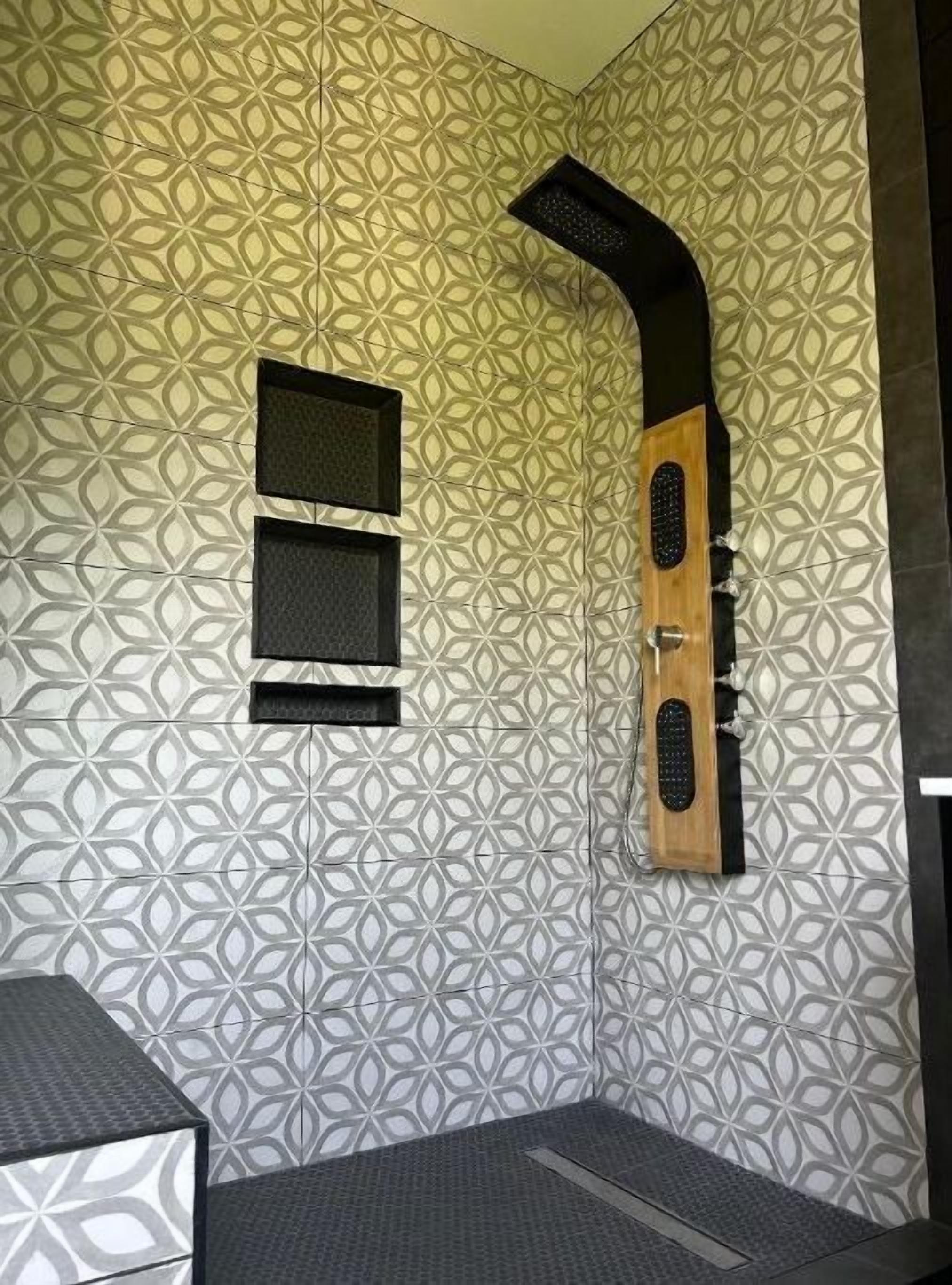A bathroom with a geometric patterned tile wall, a wooden shower enclosure, and a small window.