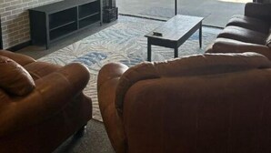 A modern living room with a fireplace, leather sofas, a TV, and a view of the beach. - NEW House on Pristine Shell Lake! Right off the ATV/Snowmobile trails! (Shell Lake)