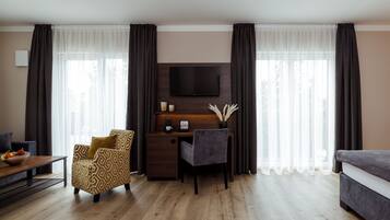 Una sala de estar moderna con un escritorio de madera, un sillón cómodo, un sofá y un televisor de pantalla plana montado en la pared.