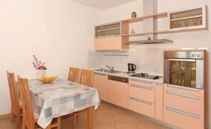 Eine kompakte Küche mit Esstisch, Stühlen, einer Kaffeemaschine und einem eingebauten Backofen.