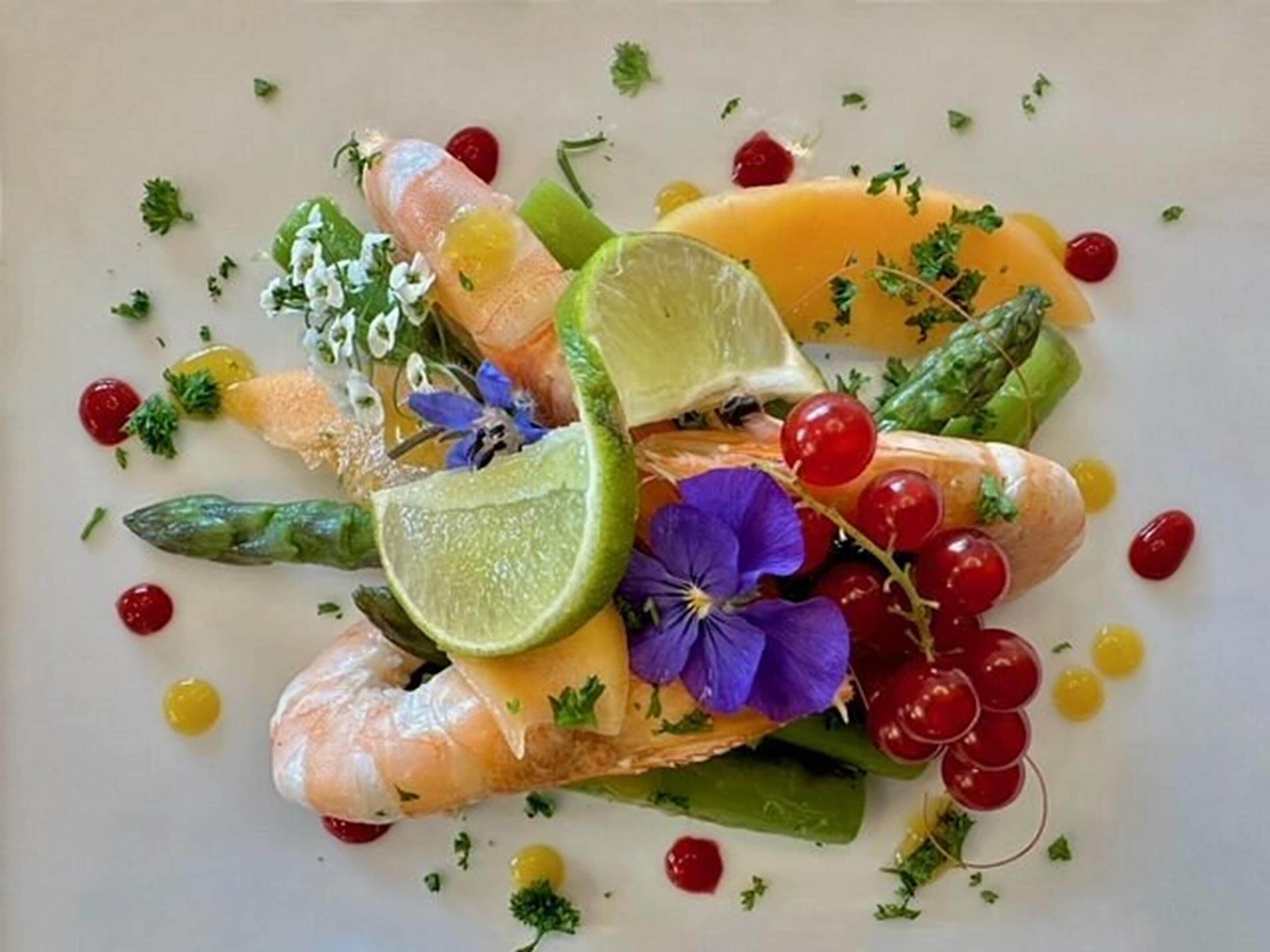 A dish with various fruits, vegetables, and herbs arranged on a plate.