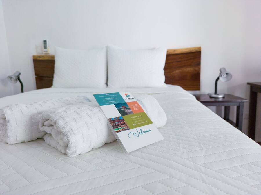 A neatly made bed with a folded white towel and a welcome card.