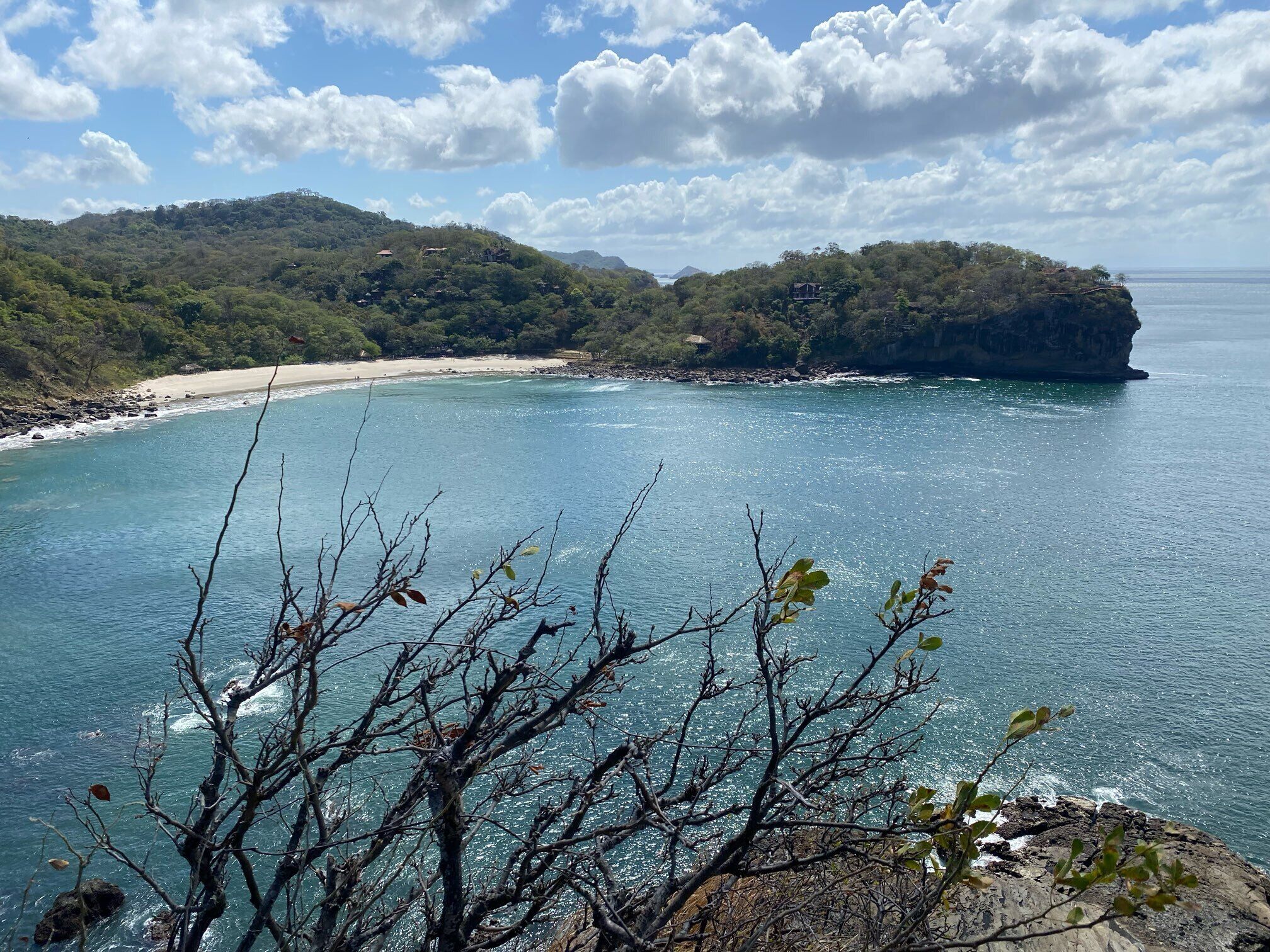 A coastal landscape with a beach, rocky cliffs, and a clear sky.