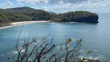A coastal landscape with a beach, rocky cliffs, and a clear sky.