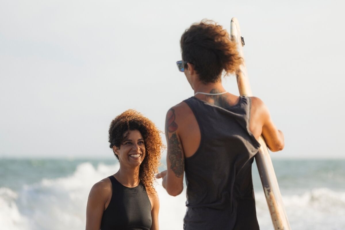 Two people on a beach with a surfboard.