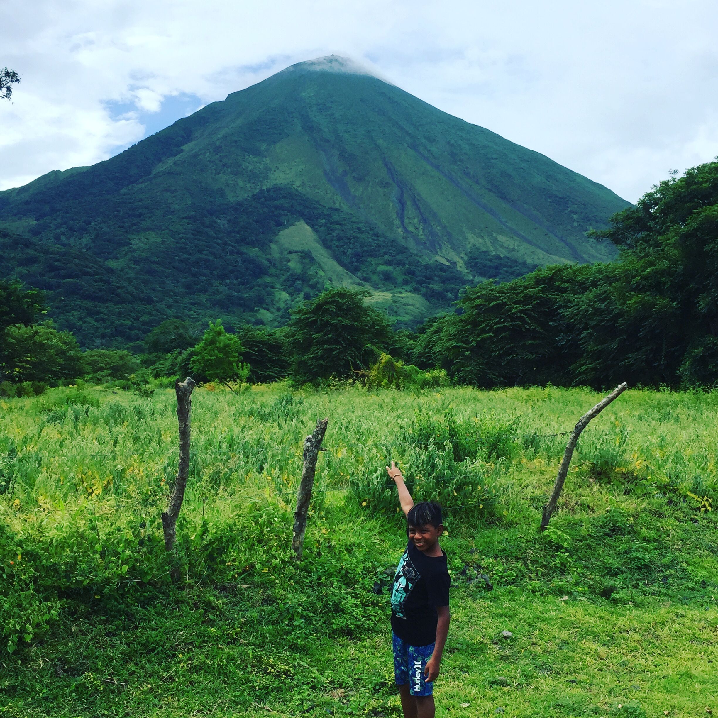 A person standing in a grassy field with a mountain in the background.