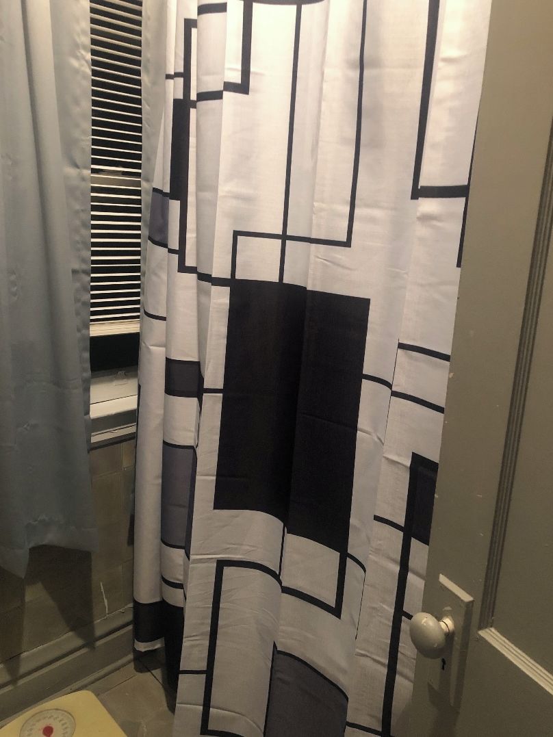 Une salle de bain avec un rideau de douche orné d’un motif géométrique.