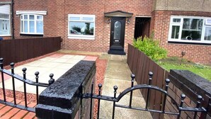 A two-story brick house with a front garden, a black front door, and a metal fence. - 5star Serviced Homes- Free Wifi & Parking, Office (Sunderland)