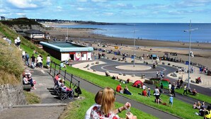 A coastal promenade with a circular park area, seating, and a view of the beach. - 5star Serviced Homes- Free Wifi & Parking, Office (Sunderland)