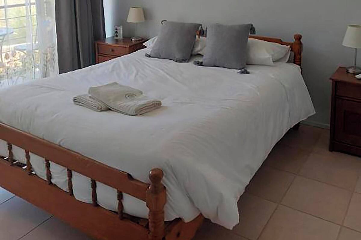 Un lit bien fait, avec des oreillers et une serviette pliée, une table de chevet avec une lampe et une fenêtre avec des rideaux.