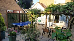 A patio area with a ping pong table, outdoor seating, and potted plants. - 23 Brandeston Close (Sudbury)
