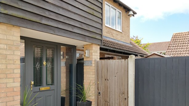 A residential property with a dark-colored front door, a wooden fence, and a potted plant beside the door. - 23 Brandeston Close (Sudbury)