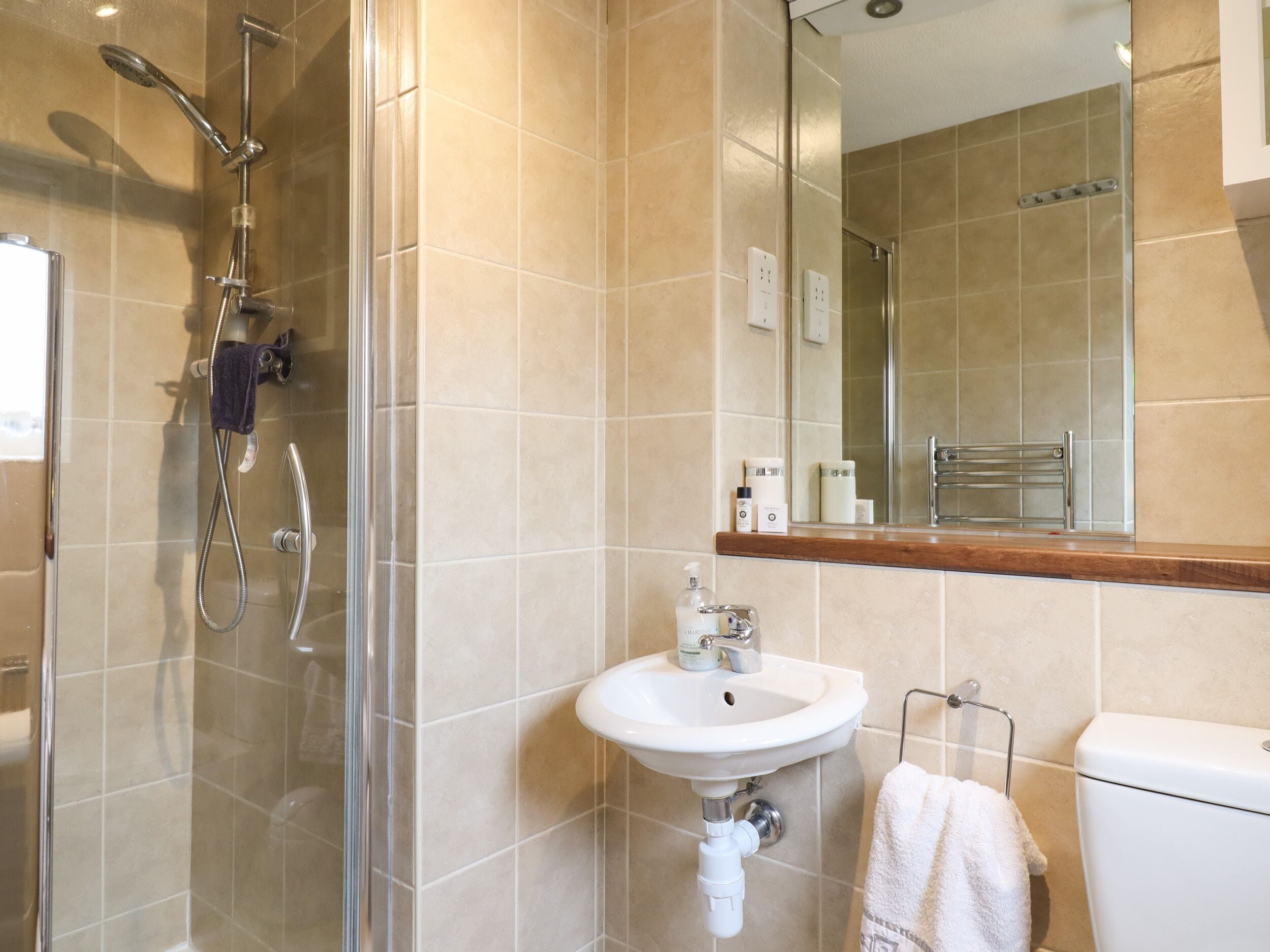 A modern bathroom with a glass-enclosed shower, a white sink, and a toilet.