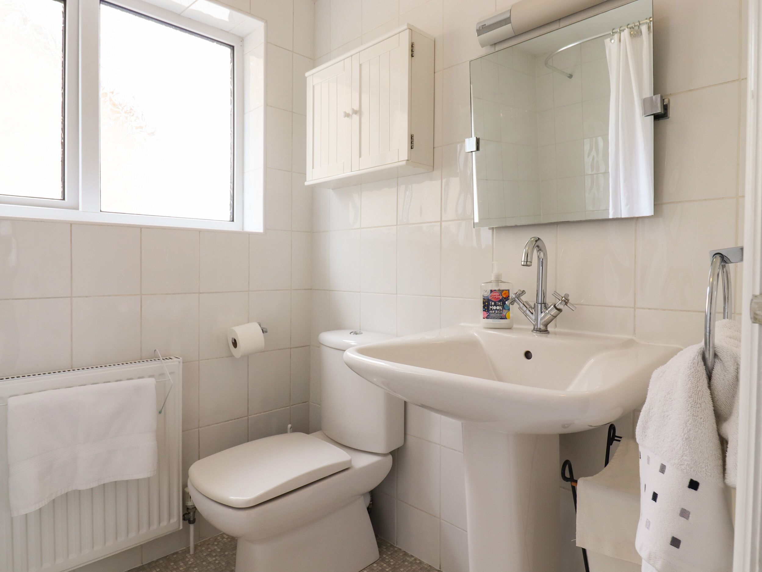 A bathroom with a toilet, sink, and window.