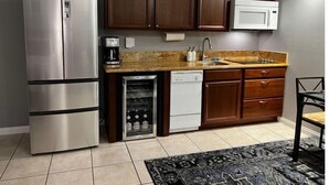Una cocina con refrigerador de acero inoxidable, lavavajillas integrado, gabinetes de madera, microondas y encimera de granito.