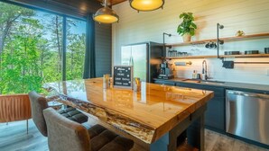 Una cocina moderna con una isla de madera, electrodomésticos de acero inoxidable y vistas al bosque.