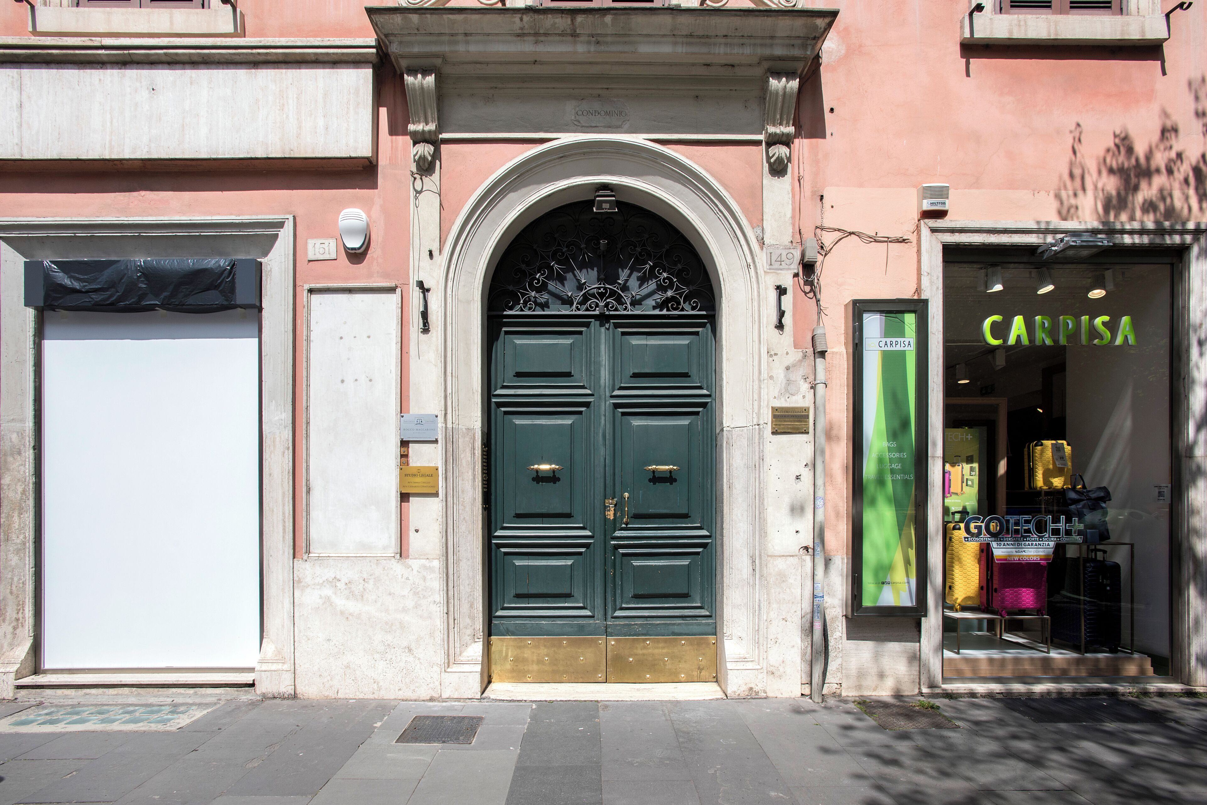A building facade with a green double door, a closed white door, and a shop with a green sign.
