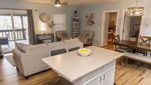 A spacious living area with a sofa, a dining table, and a kitchen island. - 4 Bed | Hot Tub | Close to IU | Pet Friendly (Bloomington)