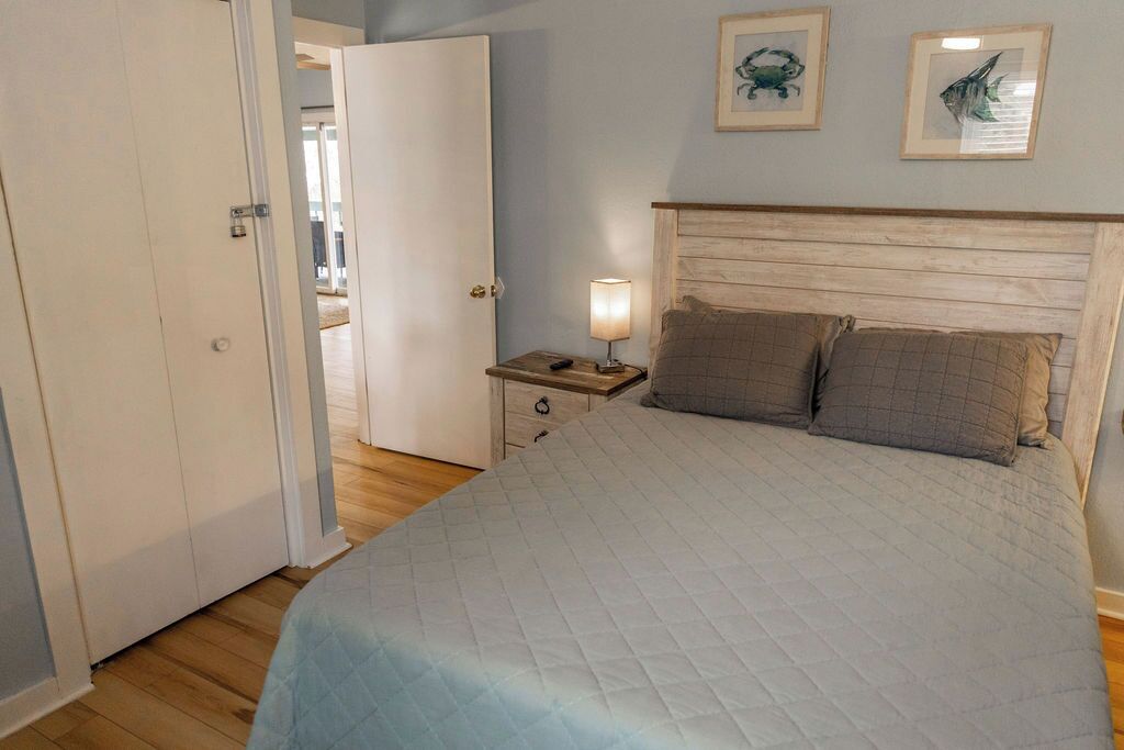 A bedroom with a bed, a nightstand, a lamp, and a door.