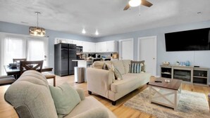 A modern living room with a sofa, armchair, and coffee table, a kitchen with appliances, and a dining area with a table and chairs. - 4 Bed | Hot Tub | Close to IU | Pet Friendly (Bloomington)