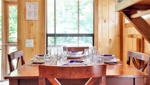 Een houten eettafel gedekt met borden, kommen en glazen, met een raam op de achtergrond.
