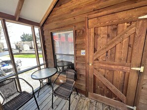 A wooden exterior with a large door, a small table, and two chairs. - Lovely Cabin in Bloomington (Bloomington)