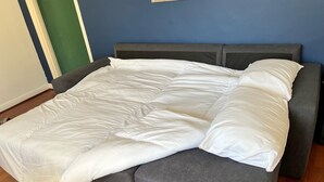 A bed with a grey headboard and footboard, white bedding, and a wooden floor. - Spacious 1-bed - Coolest Neighbourhood in Brighton (Brighton)