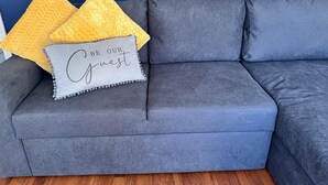 A grey sectional sofa with two yellow pillows and a grey pillow with the text "BE OUR guest". - Spacious 1-bed - Coolest Neighbourhood in Brighton (Brighton)