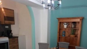 A dining area with a wooden table and chairs, a kitchen with cabinets and appliances, and a teal accent wall.