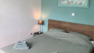 A bedroom with a bed, a nightstand, a lamp, and a floral artwork on the wall.