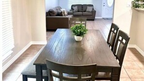 Zona pranzo con un tavolo e sedie in legno scuro, un lampadario e una pianta in vaso.