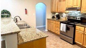 Una cucina con piani in granito, mobili in legno, un fornello in acciaio inossidabile e una macchina per il caffè.