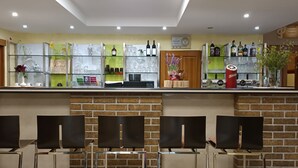 A bar area with a brick wall, seating, and various bottles and glasses on shelves. - Hotel Vintíř (Hartmanice)