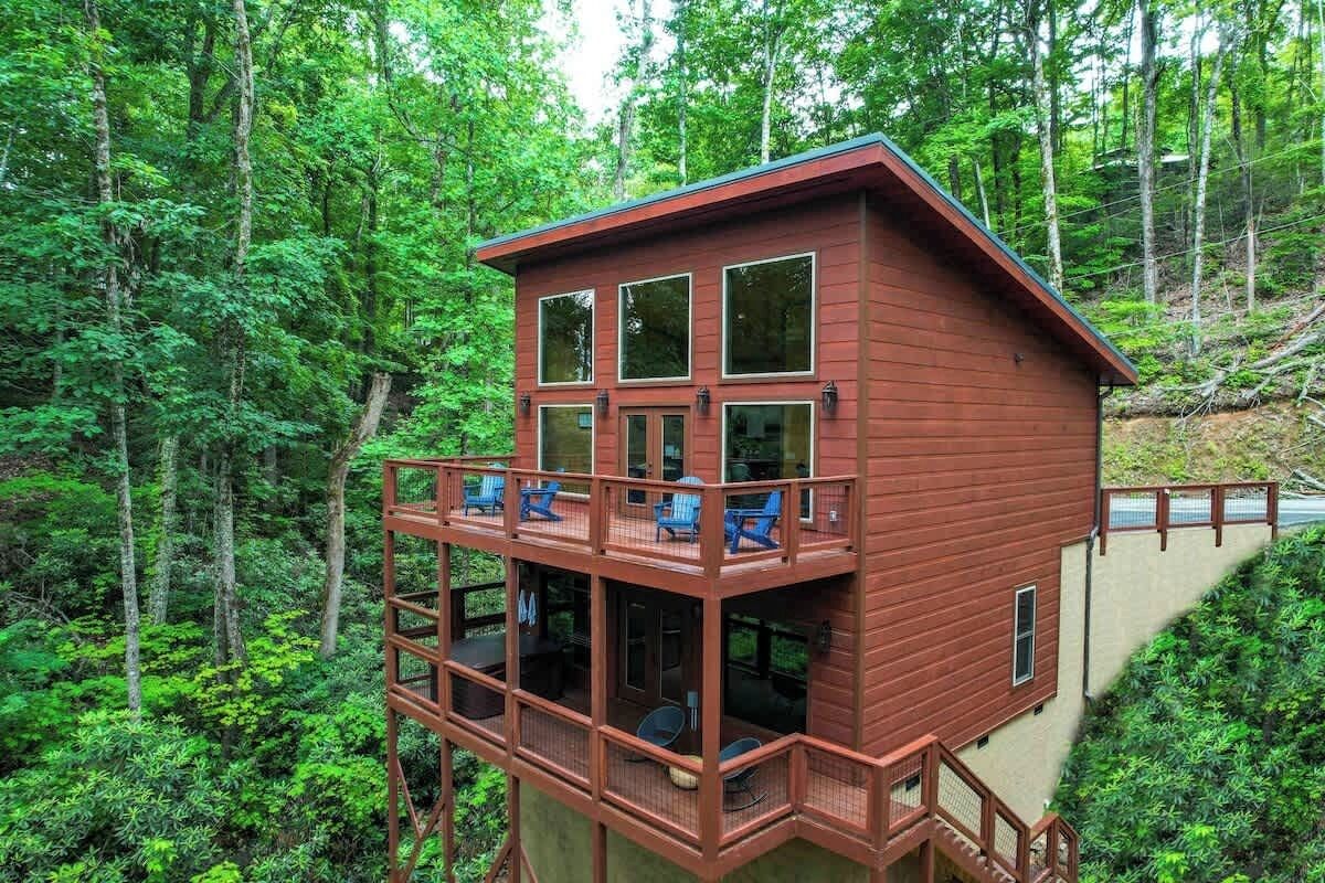 Eine zweistöckige Holzhütte mit Balkon, umgeben von dichtem Wald.