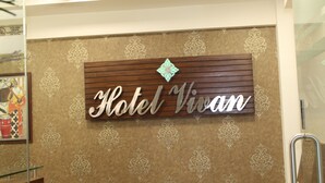 Señal de Hotel Vivan con un fondo decorativo y un ventilador de techo.