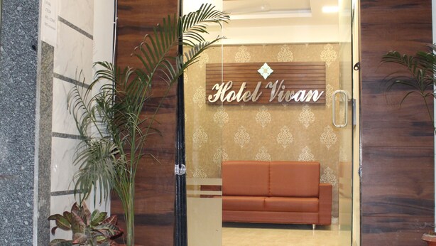 Entrada de un hotel con fachada de madera, puerta de cristal y un letrero que dice 'Hotel Vivan'.