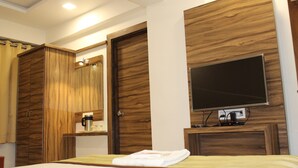 Habitación de hotel con cama, televisor montado en la pared, puertas de madera y zona de ducha.
