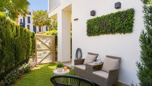 A patio with wicker furniture, a small table, and a green wall with plants. - Rota Punta Candor Terrace Playa 3 Bajo C (AN)