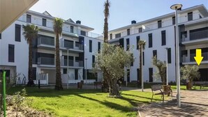 A modern multi-story residential building with balconies, a well-maintained lawn, and a clear sky. - Rota Punta Candor Terrace Playa 3 Bajo C (AN)