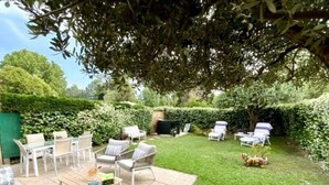 Eine Terrasse mit Gartenmöbeln, Fliesenboden und einem gepflegten Rasen.