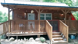 A wooden cabin with a porch, a door, and a window.