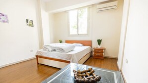 Une chambre à coucher avec un lit, une table de chevet, une petite plante et un plancher en bois.