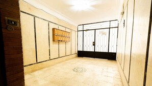 A hallway with a tiled floor, a wooden cabinet with multiple compartments, and a metal gate with a lock. - Lily Mint Comfy 3BR W/Sitting room TV Apartment (Maadi as Sarayat Al Gharbeyah)