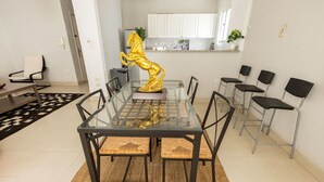 A dining area with a glass table and metal chairs, a golden horse sculpture, and a kitchen in the background. - Lily Mint Comfy 3BR W/Sitting room TV Apartment (Maadi as Sarayat Al Gharbeyah)