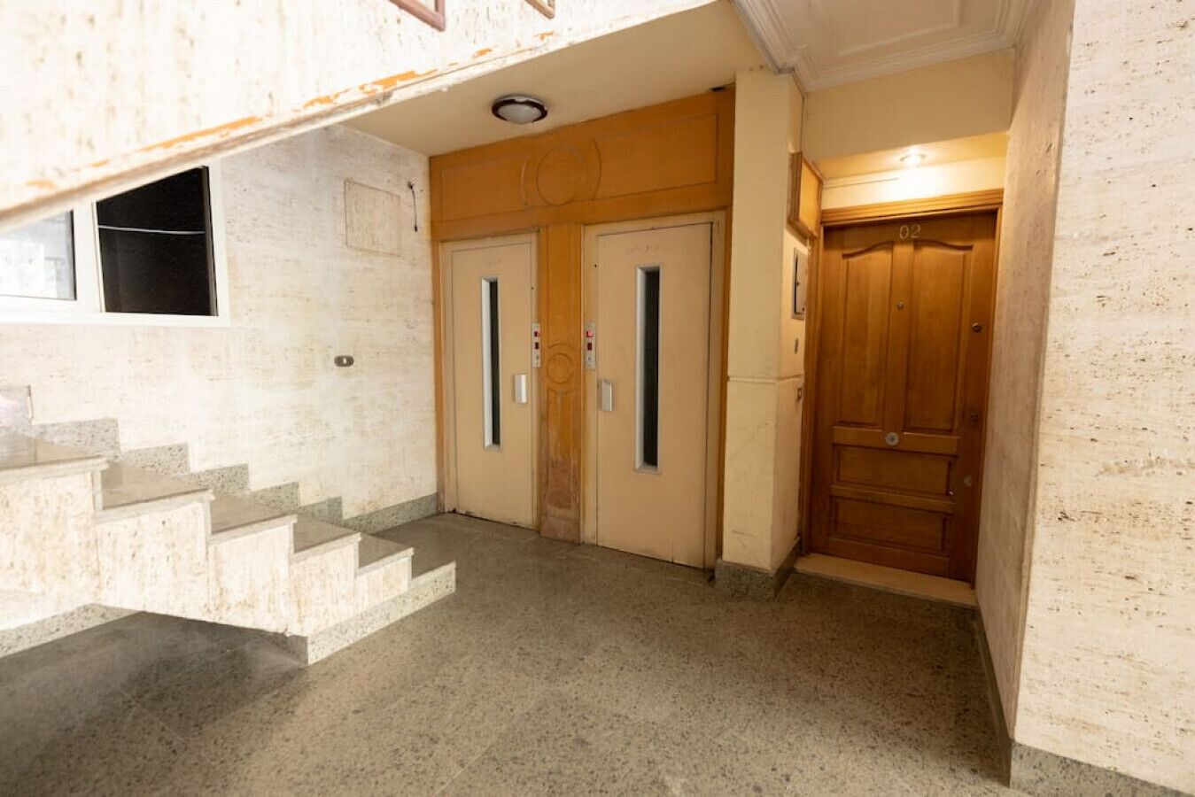Un pasillo con una escalera que lleva a una puerta.