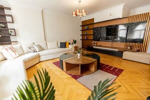 A modern living room with a sofa, coffee table, and TV. - Oak Orchid Opulent 3BR Apartment (Maadi as Sarayat Al Gharbeyah)