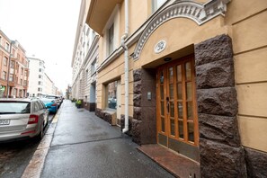 A building with a stone facade, a wooden door with glass panels, and a number '52' sign.