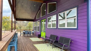 A covered deck with wooden flooring and outdoor seating.