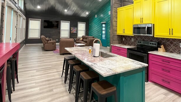 A modern kitchen with a central island, bright yellow cabinets, and a large window.