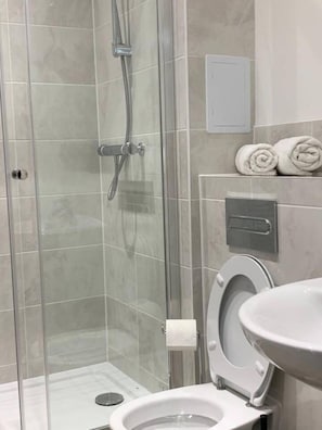 A modern bathroom with a glass-enclosed shower, a toilet, and a sink. - Inviting 2-bed Apartment in Grays (Grays)